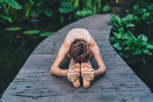 Unrecognizable woman doing yoga on pier wooden way