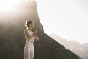 Woman is practicing yoga, meditating on the beach.